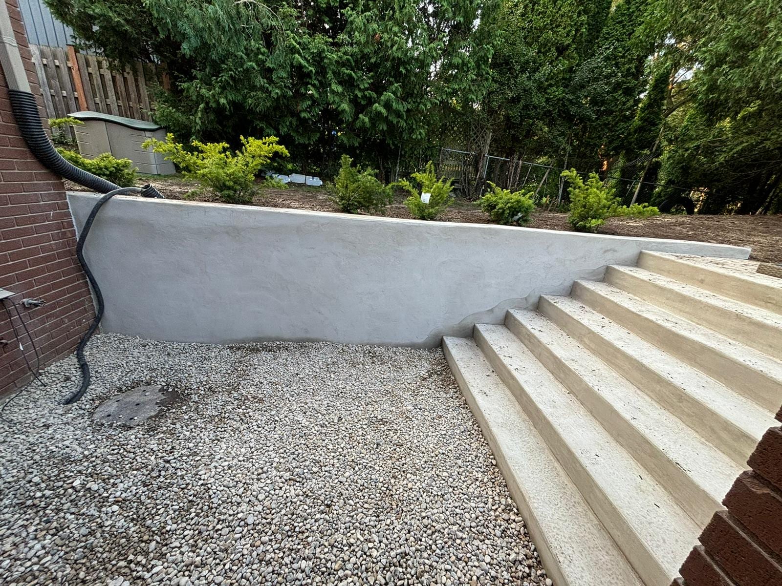 Smooth parged poured concrete retaining wall with concrete steps in a landscaped backyard