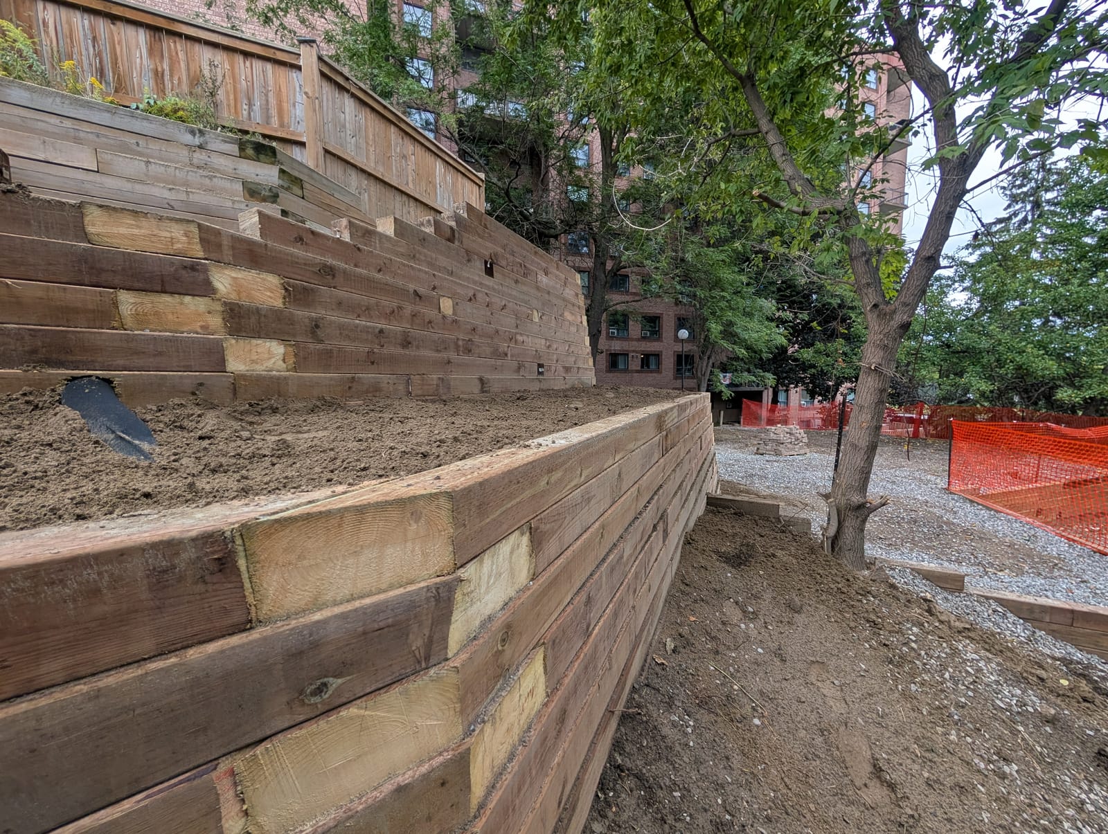 Tiered timber retaining wall stepping back to hold soil beside a fenced urban backyard